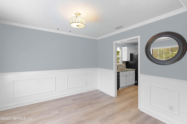 unfurnished dining area featuring ornamental molding, visible vents, and light wood-type flooring