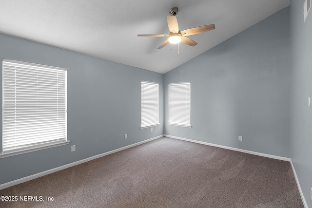 carpeted spare room with lofted ceiling, a ceiling fan, baseboards, and a healthy amount of sunlight