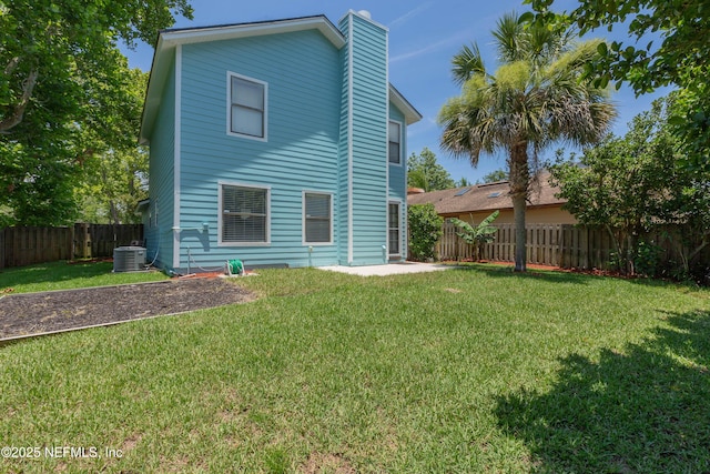 rear view of house featuring a yard, a fenced backyard, cooling unit, and a chimney