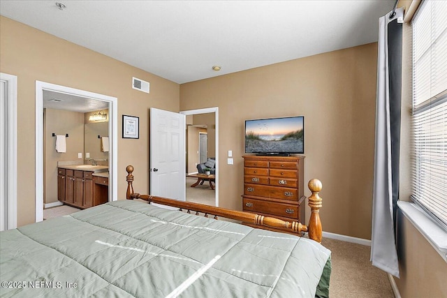 carpeted bedroom with ensuite bath and sink