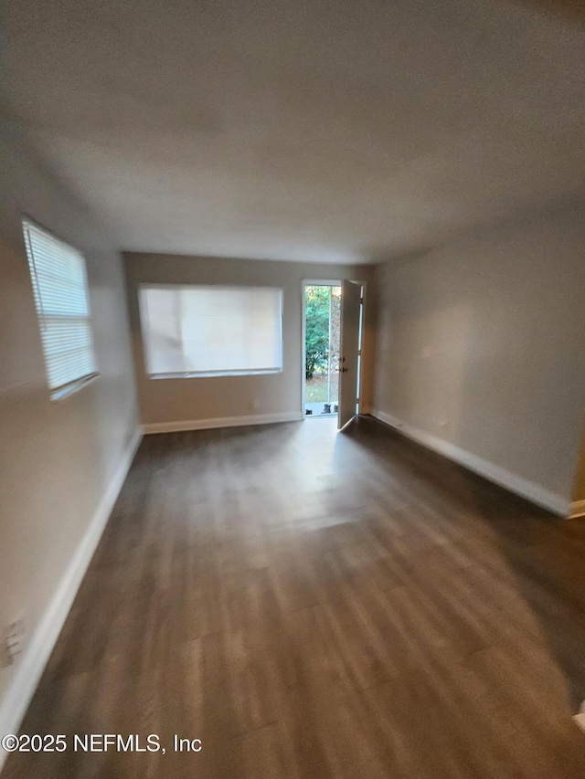 unfurnished room featuring dark wood-style floors and baseboards