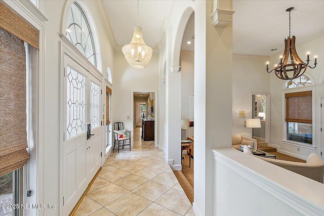 foyer featuring a chandelier, a towering ceiling, ornamental molding, plenty of natural light, and light tile patterned flooring