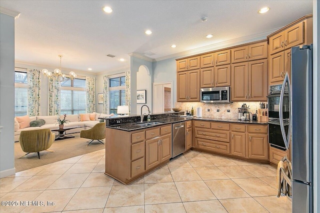 kitchen featuring appliances with stainless steel finishes, a sink, a peninsula, crown molding, and a chandelier