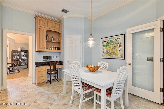 dining space featuring crown molding and light tile patterned flooring