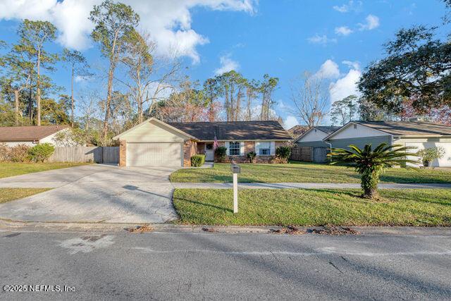 single story home featuring a garage and a front lawn