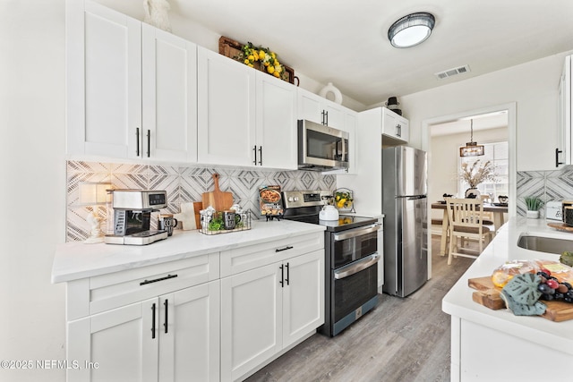 kitchen featuring stainless steel appliances, white cabinets, and decorative backsplash