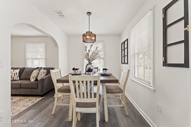 dining space featuring arched walkways, visible vents, dark wood finished floors, and baseboards