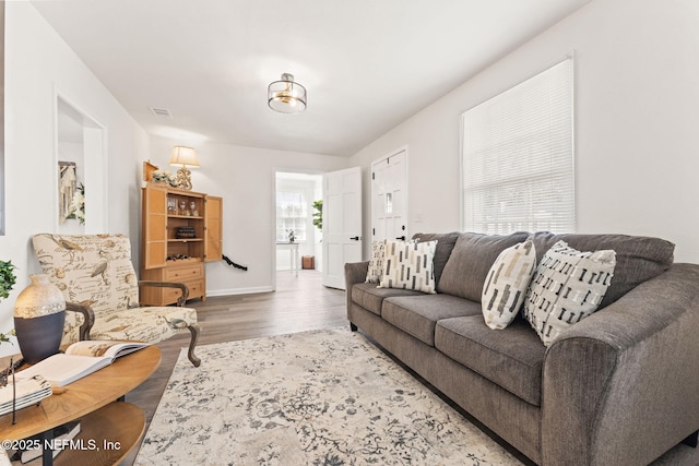 living area with wood finished floors, visible vents, and baseboards