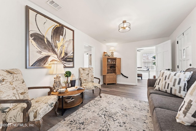 living area featuring baseboards, visible vents, and dark wood-style flooring