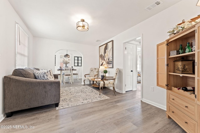 sitting room featuring baseboards, visible vents, arched walkways, and wood finished floors