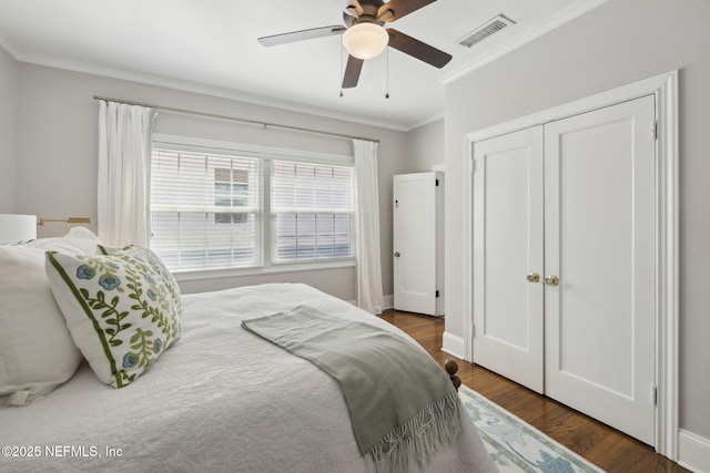 bedroom featuring ceiling fan, dark wood-type flooring, crown molding, and a closet