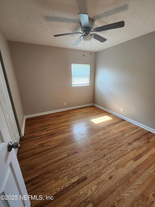 spare room with ceiling fan, a textured ceiling, baseboards, and wood finished floors