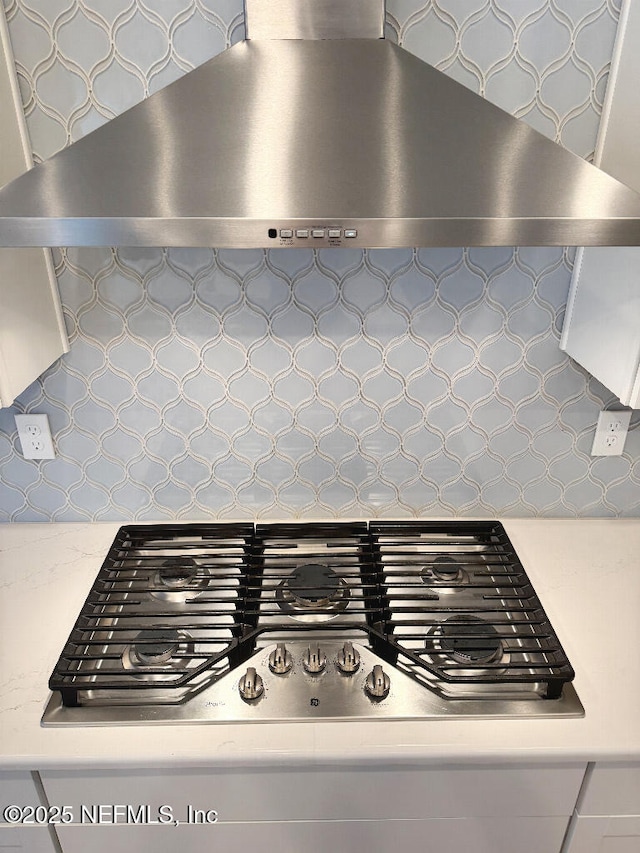 room details featuring backsplash, wall chimney range hood, and stainless steel gas cooktop