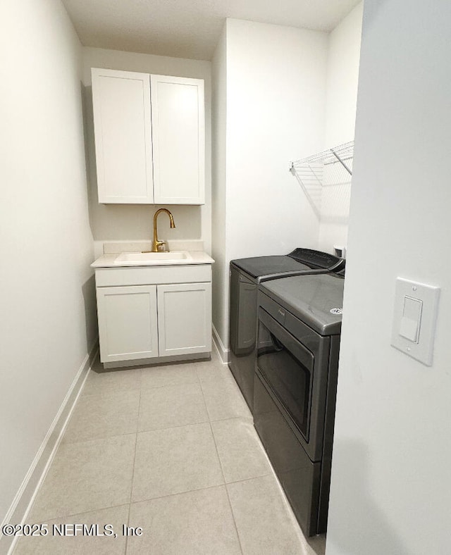 washroom featuring washing machine and dryer, sink, cabinets, and light tile patterned floors