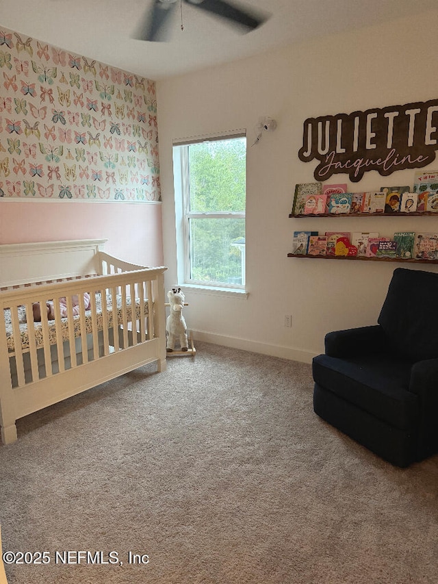 bedroom featuring ceiling fan, a nursery area, and carpet flooring