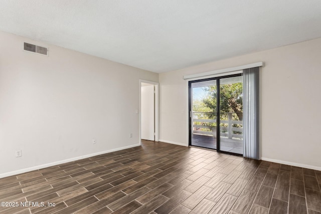 unfurnished room with wood finish floors, visible vents, and baseboards