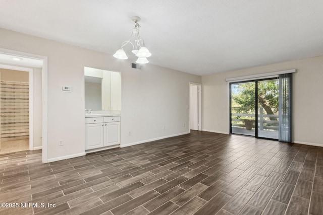 empty room with baseboards, wood tiled floor, visible vents, and a notable chandelier