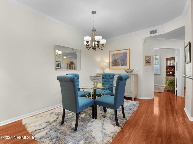 4306 Serena Cir, Saint Augustine, FL 32084 - dining area with baseboards, an inviting chandelier, crown molding, visible vents, and wood finished floors