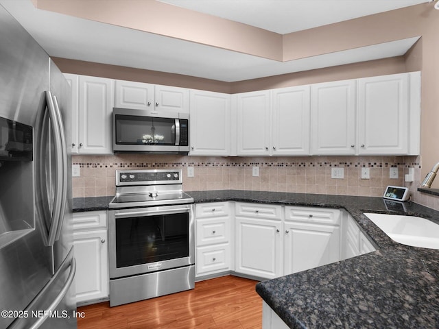 4306 Serena Cir, Saint Augustine, FL 32084 - kitchen with light wood-style flooring, a sink, appliances with stainless steel finishes, white cabinetry, and decorative backsplash