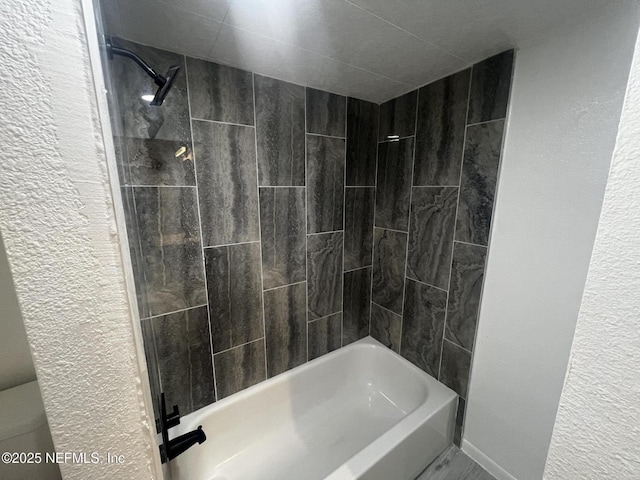 full bathroom with toilet, shower / tub combination, and a textured wall