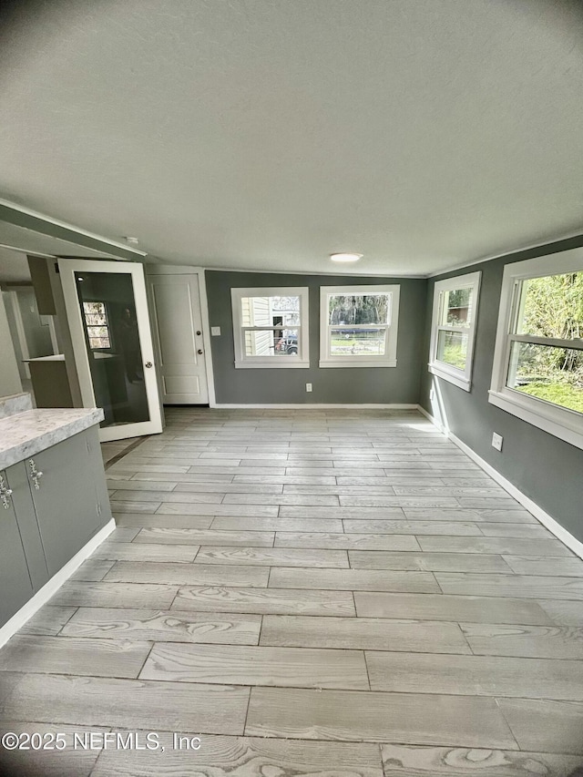 unfurnished living room with a healthy amount of sunlight, light wood-style flooring, and baseboards