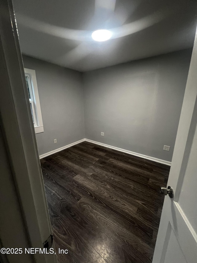 empty room with dark wood-style flooring and baseboards