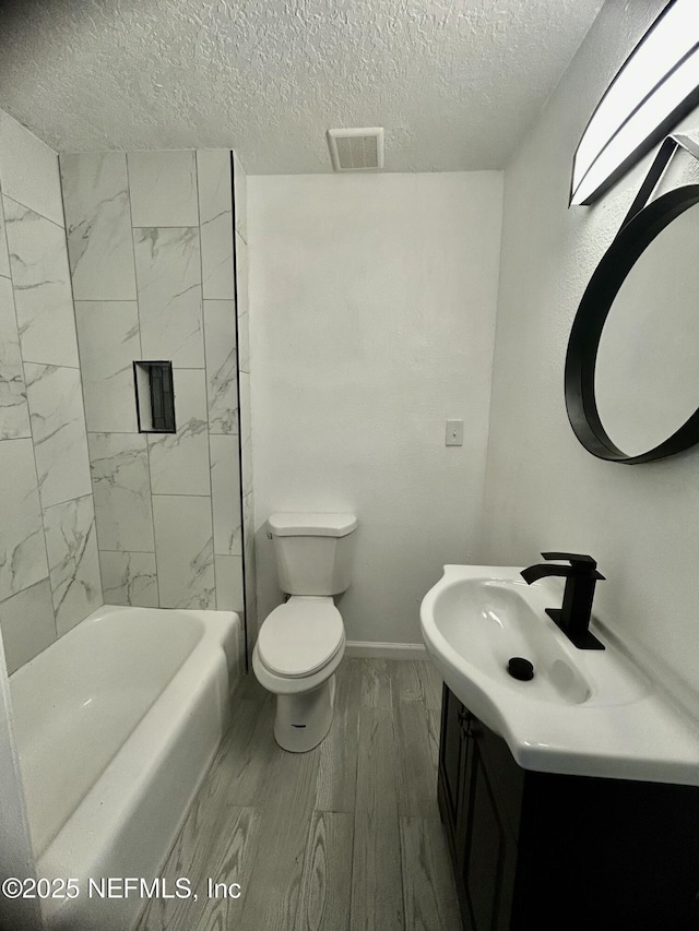 full bathroom featuring a textured ceiling, toilet, wood finished floors, visible vents, and vanity