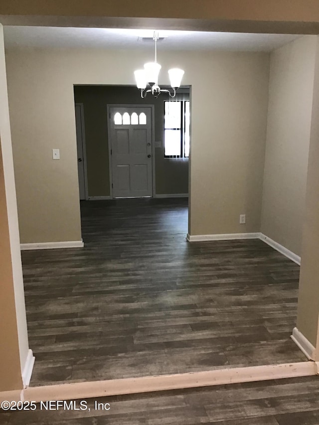 foyer entrance featuring baseboards, dark wood finished floors, and an inviting chandelier