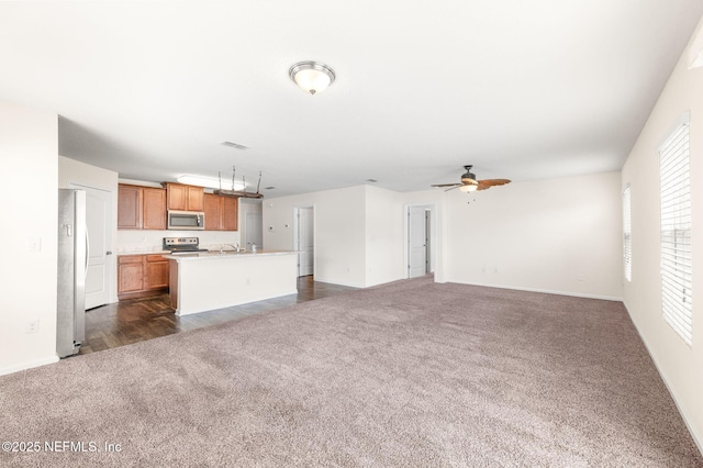 unfurnished living room with ceiling fan and dark colored carpet