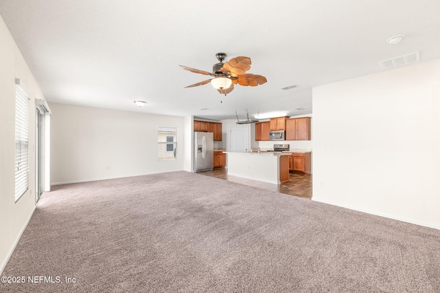 unfurnished living room with dark carpet, a wealth of natural light, and ceiling fan