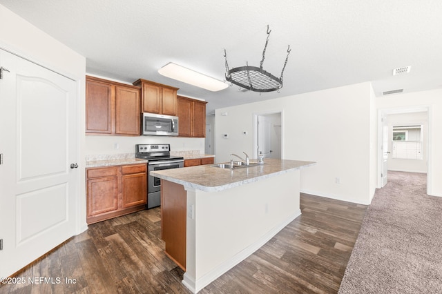 kitchen featuring a center island with sink, stainless steel appliances, a textured ceiling, sink, and dark hardwood / wood-style floors