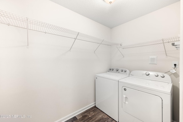 clothes washing area with dark wood-type flooring, washer and clothes dryer, and a textured ceiling