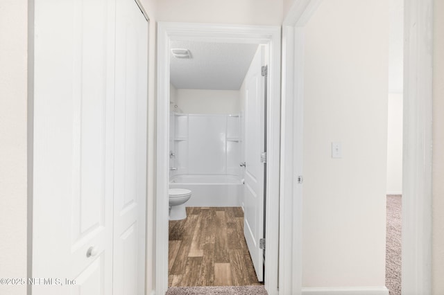 bathroom featuring a textured ceiling, toilet, hardwood / wood-style floors, and shower / bath combination