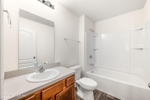 full bathroom featuring vanity, washtub / shower combination, a textured ceiling, toilet, and hardwood / wood-style flooring