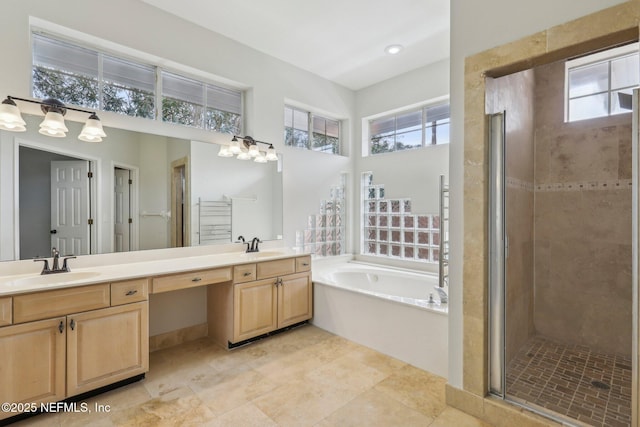 full bathroom featuring a sink, double vanity, a shower stall, and a garden tub