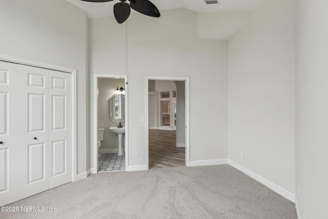 unfurnished bedroom featuring ensuite bathroom, light carpet, visible vents, baseboards, and a closet