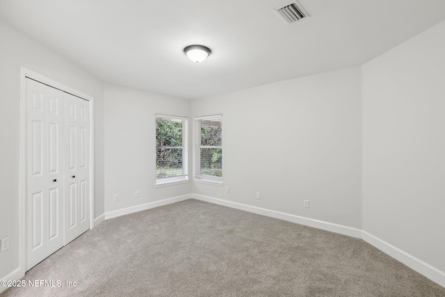 unfurnished bedroom featuring carpet floors, a closet, visible vents, and baseboards