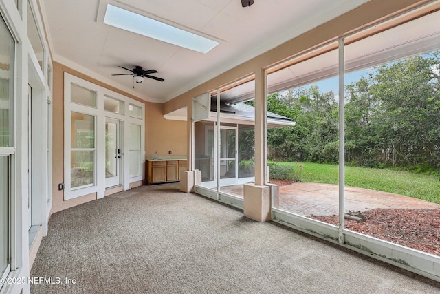 unfurnished sunroom featuring a skylight and a ceiling fan