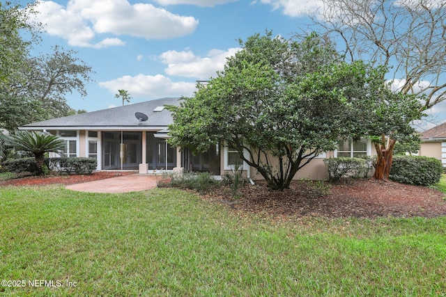 back of property featuring a sunroom, roof with shingles, a lawn, stucco siding, and a patio area