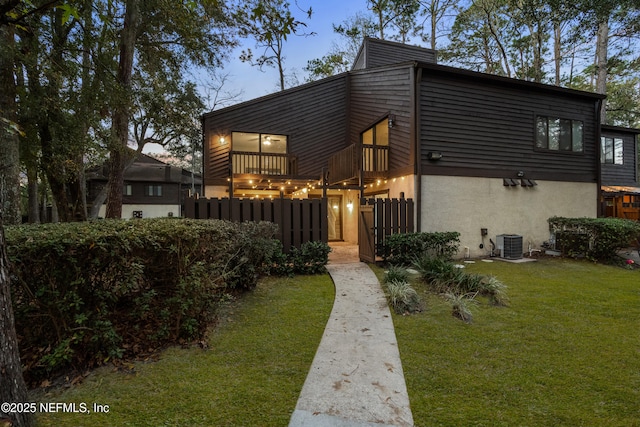 view of front of house featuring a lawn, central AC unit, and a balcony