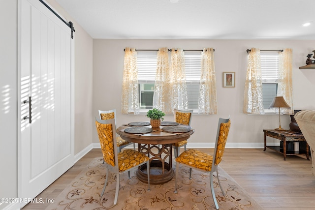 dining room with plenty of natural light, a barn door, and light wood finished floors