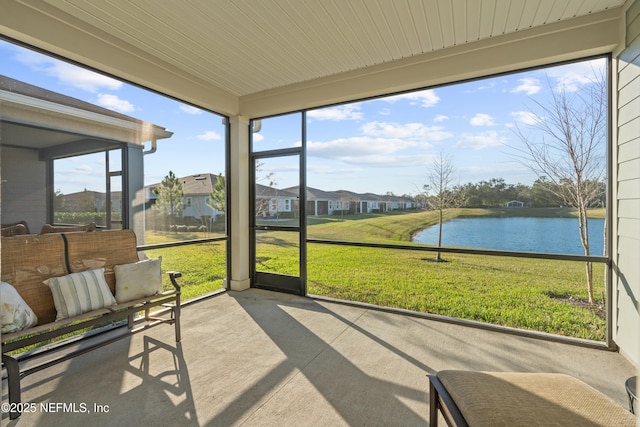 sunroom / solarium featuring a water view and a residential view