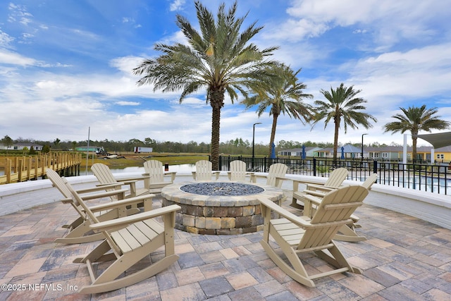 view of patio featuring a water view, an outdoor fire pit, and fence