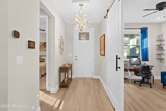 foyer entrance with ceiling fan with notable chandelier, light wood-style flooring, and baseboards