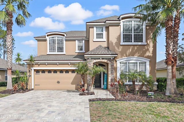 view of front of home with stone siding, roof with shingles, an attached garage, decorative driveway, and stucco siding