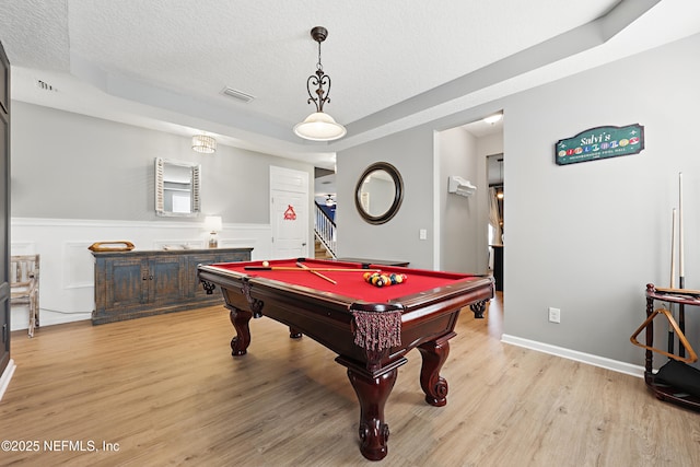 recreation room with a textured ceiling, visible vents, a wainscoted wall, and light wood-style flooring