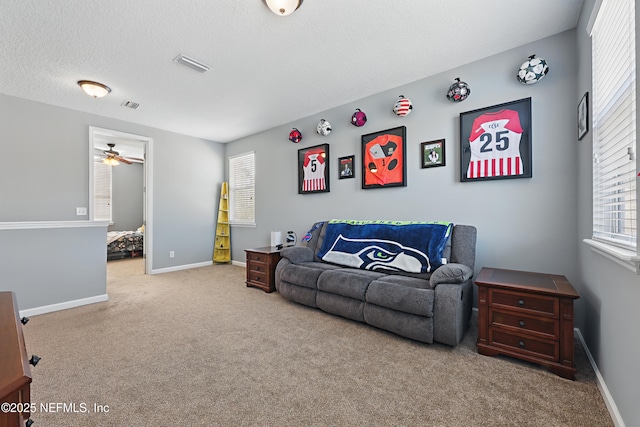 living room featuring light carpet, a textured ceiling, visible vents, and baseboards