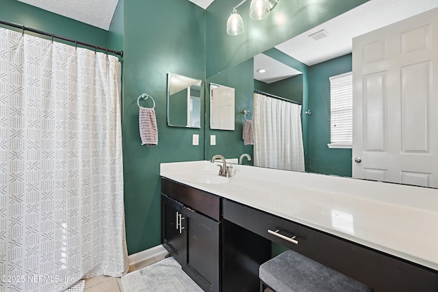 bathroom with visible vents, vanity, a textured ceiling, tile patterned flooring, and baseboards