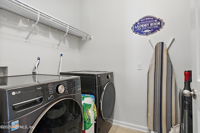 laundry area featuring laundry area, baseboards, washing machine and clothes dryer, and light tile patterned floors