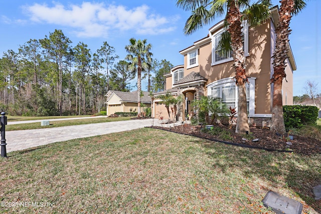 view of front of house featuring a garage, driveway, a front lawn, and stucco siding